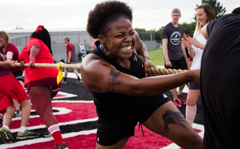 A student grimacing as she pulls on a rope for tug-of-war