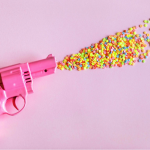 a pink gun shooting rainbow sprinkles out of it