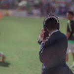 Man with headphones and a mic on the sidelines of a soccer game