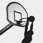 Silhouette of a man dunking a basketball