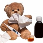 A teddy bear with a tissue, medicine, a thermometer, and other flu stuff