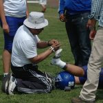 Trainer helping football player