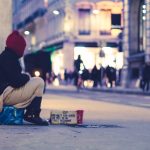 A homeless woman sitting on the sidewalk.