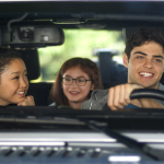 three teens riding in a car together smiling