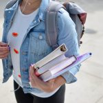 Girl carrying books and a backpack