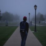 A person walking down a foggy sidewalk