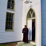 Female pastor standing in front of the church doors