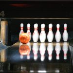 A bowling ball rolling towards pins on a lane